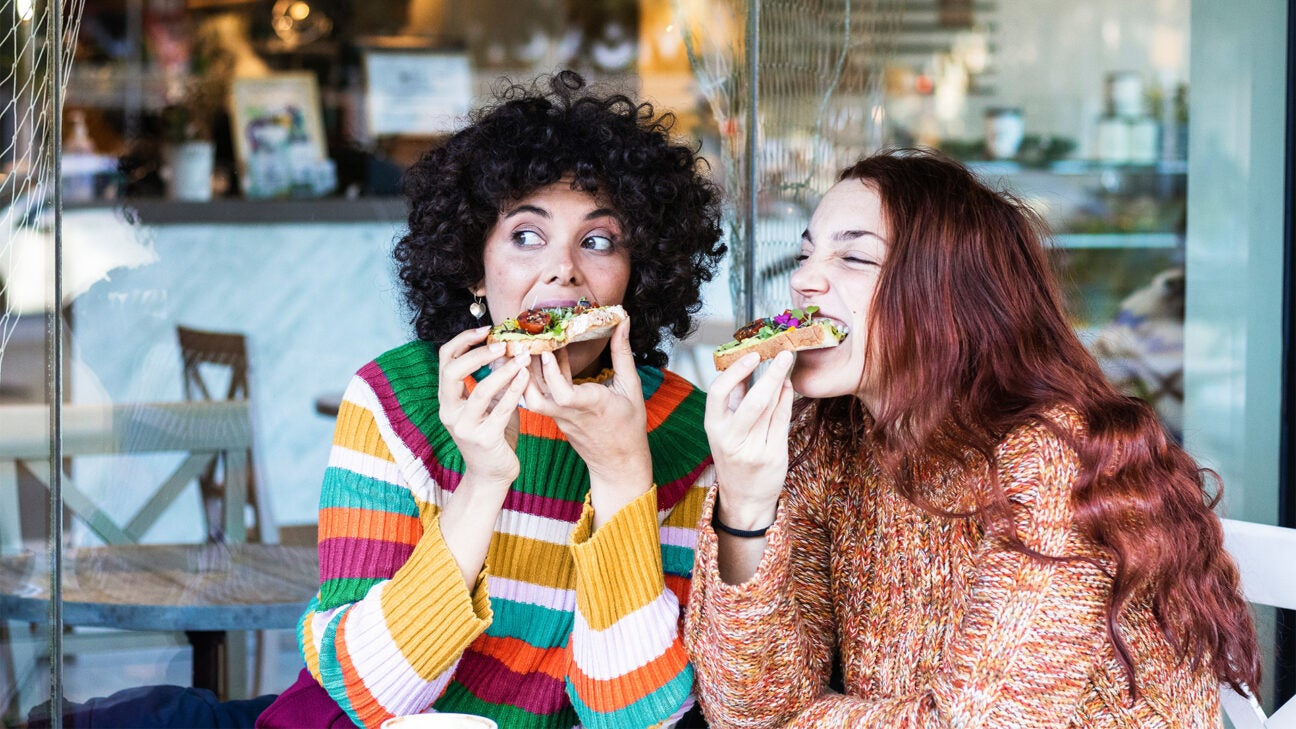 Two women seen eating a meal together.