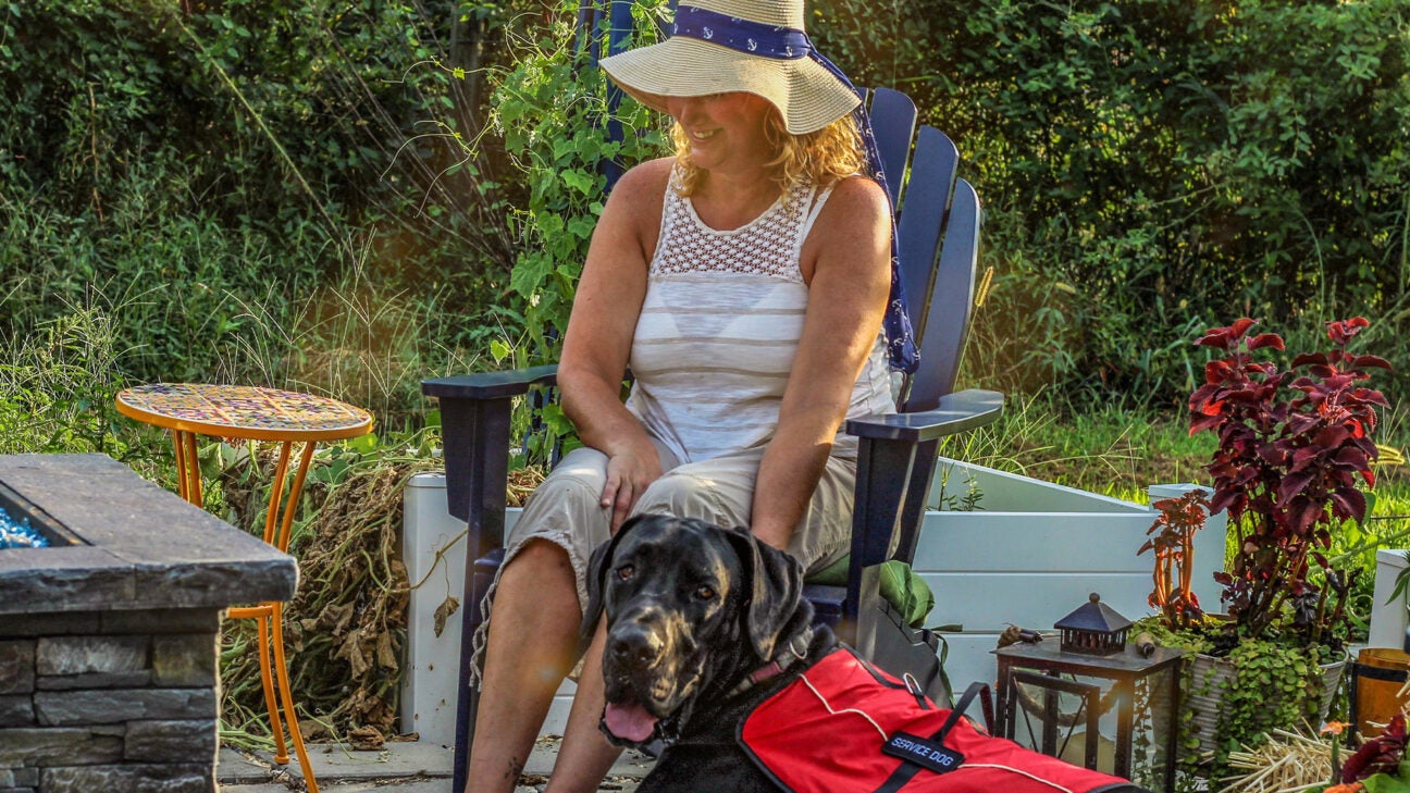 A woman is seen here with a service dog outdoors.