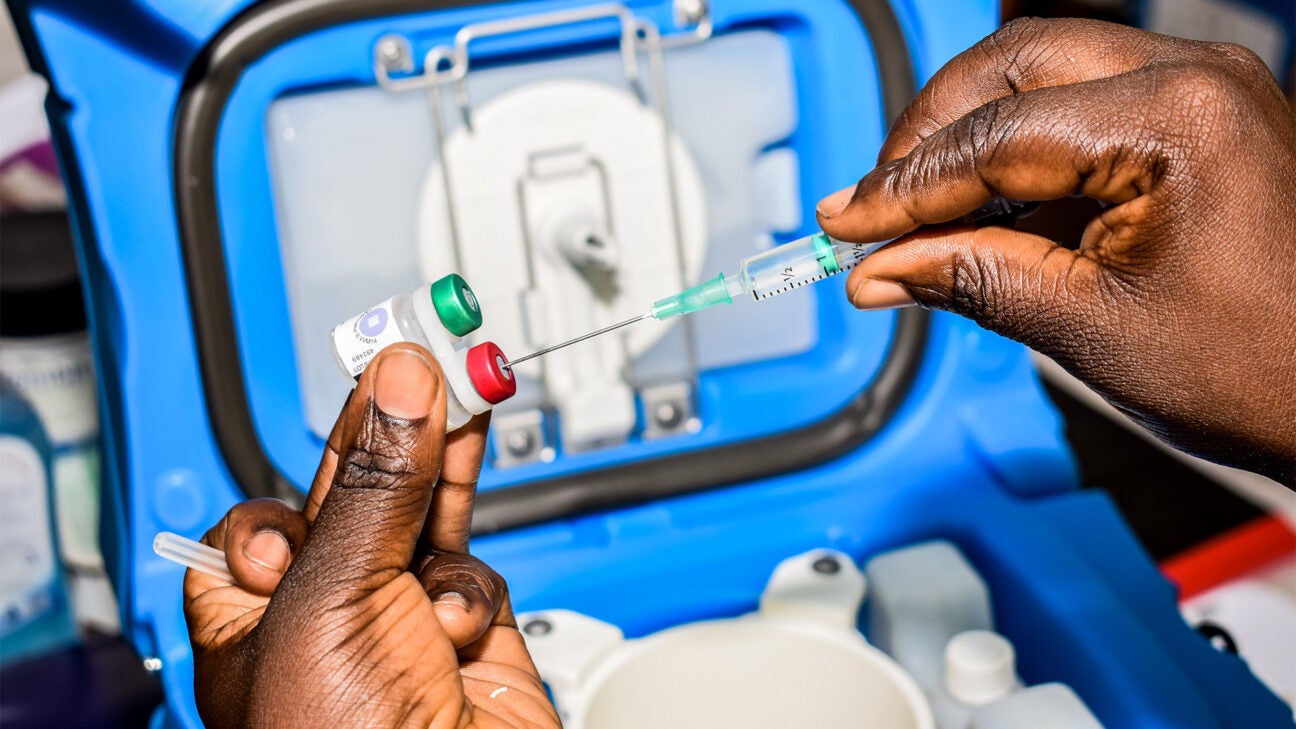 A medical professional fills a vaccine syringe