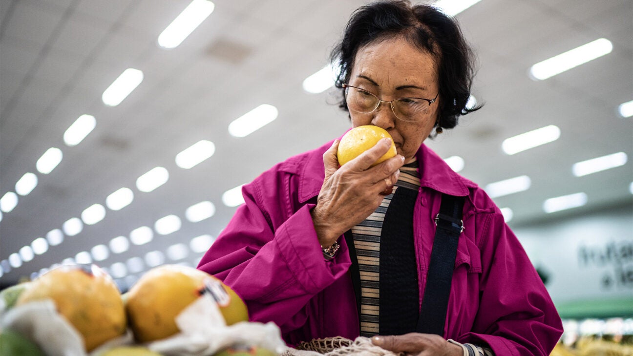 A woman smelling a piece of fruit.