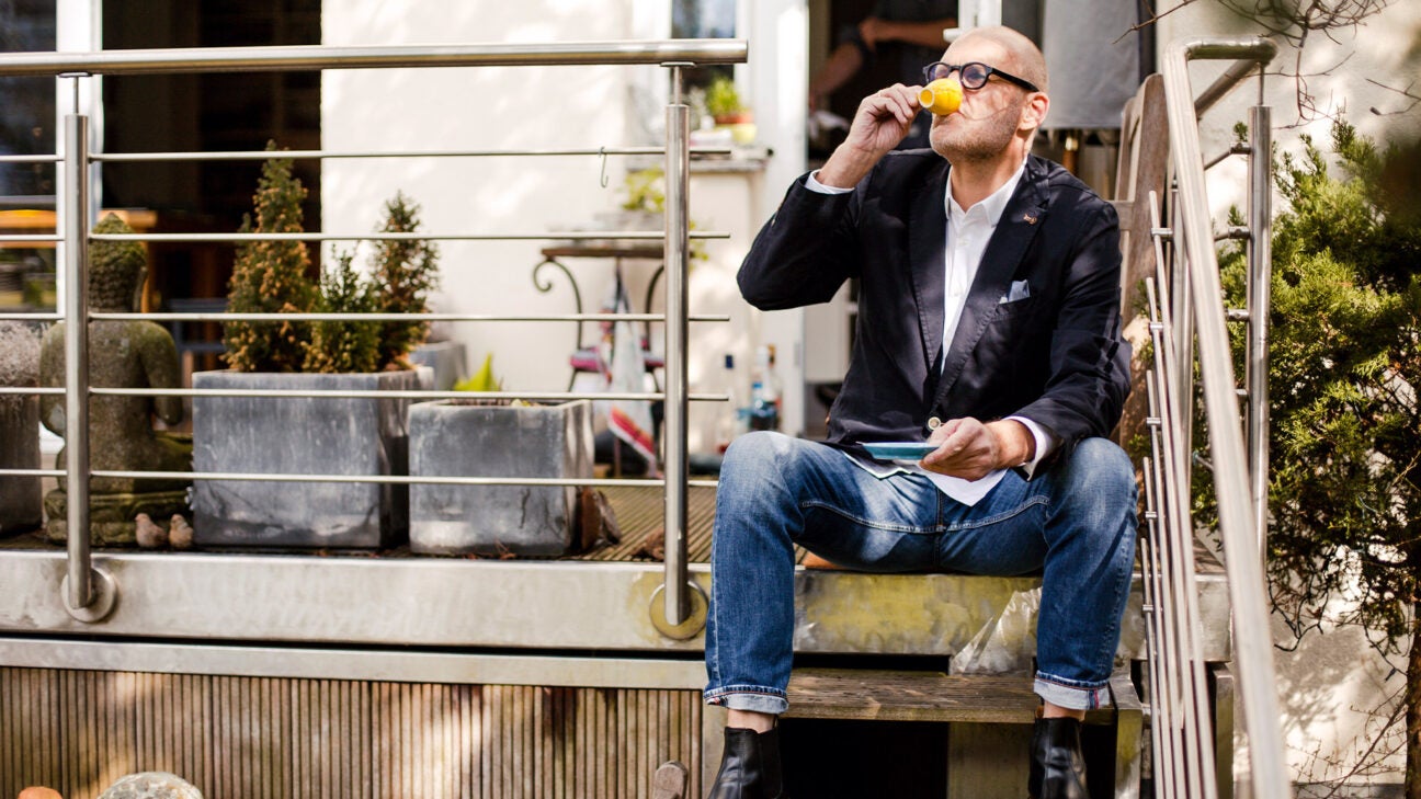 A man drinks espresso in the stairs.