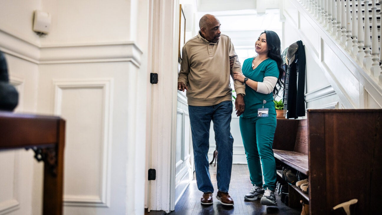 A man is helped by a female healthcare worker.