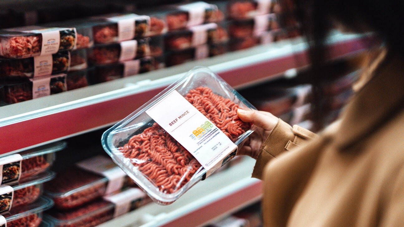 A person holds a package of red meat. 