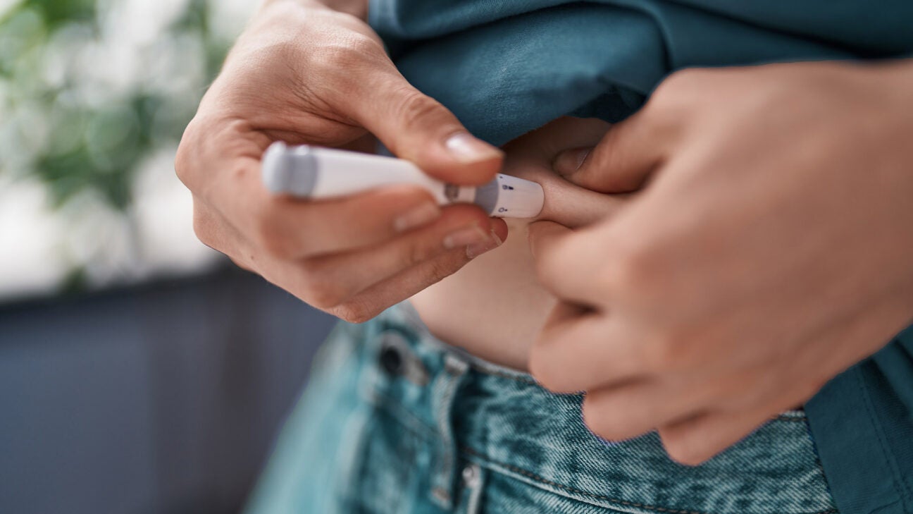 A person injects medication into their abdomen.