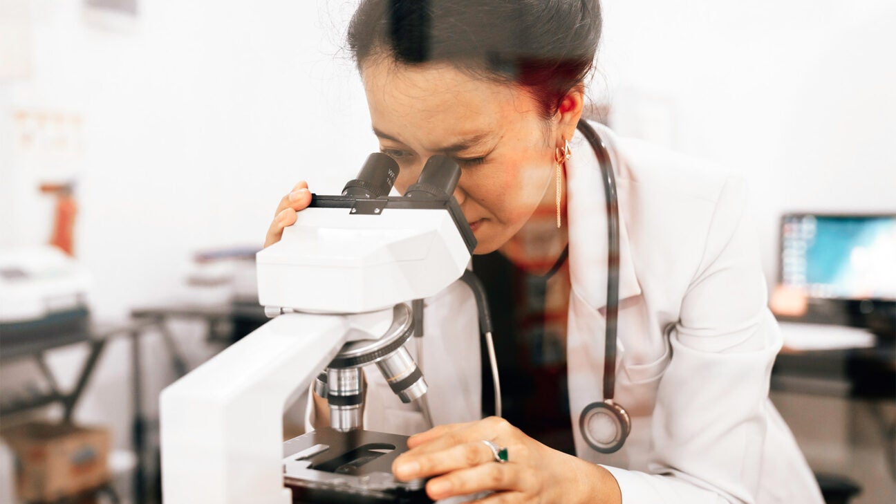 A scientist looks through a microscope.